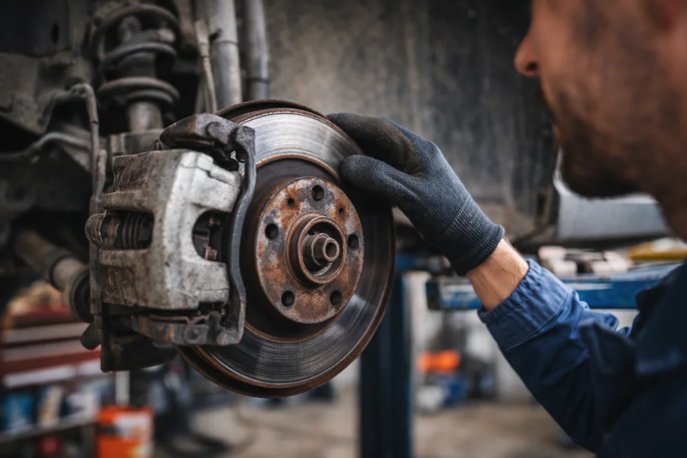 Mecánico revisando frenos del coche en taller mecánico de Guadarrama