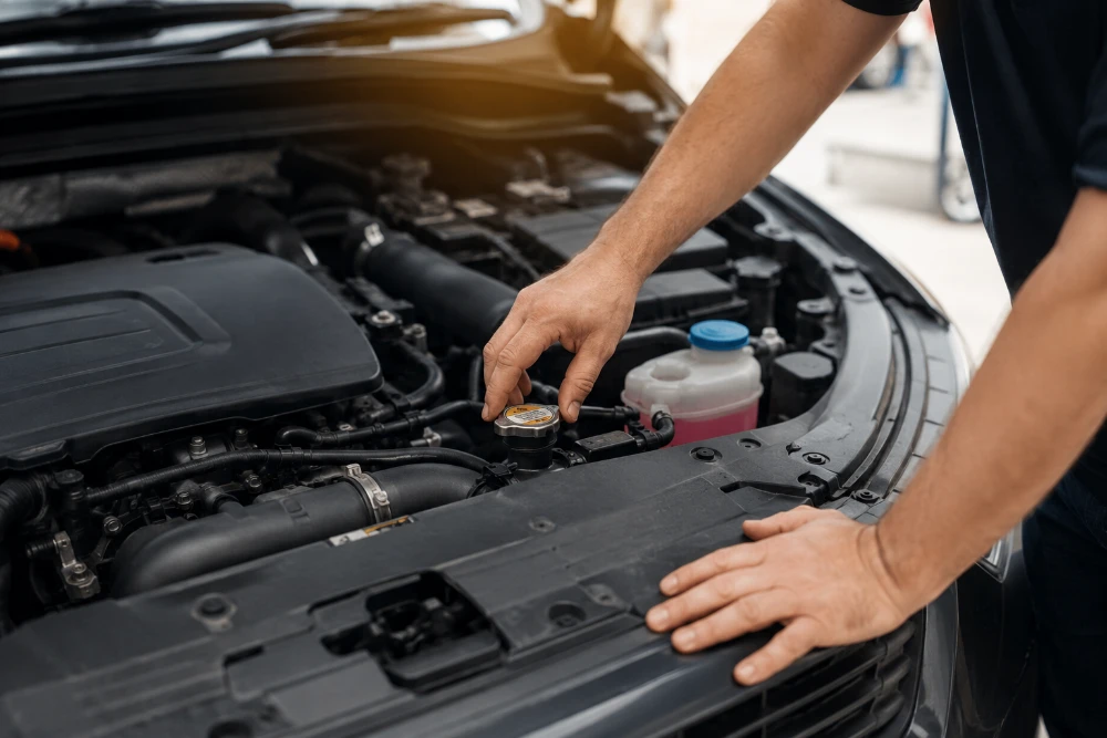 Mecánico revisando el sistema del motor de un coche antes del verano para prevenir averías y garantizar una conducción segura en Guadarrama.